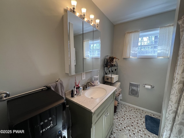 bathroom featuring plenty of natural light, vanity, and baseboards