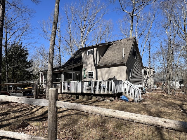 view of front facade featuring a shingled roof, a deck, and a sunroom