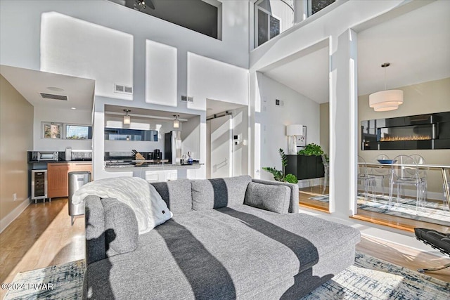 living room featuring hardwood / wood-style floors, a towering ceiling, and beverage cooler