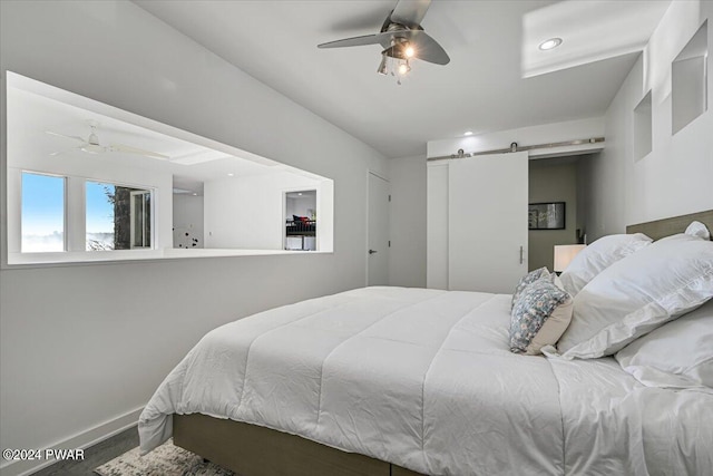 bedroom with a barn door and ceiling fan