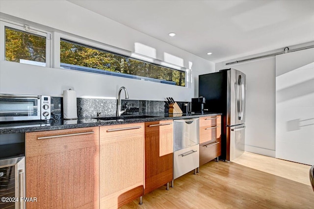 kitchen with stainless steel fridge, light hardwood / wood-style floors, beverage cooler, and sink