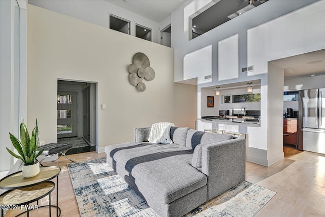 living room featuring a towering ceiling, light hardwood / wood-style floors, and sink