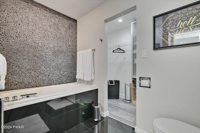 bathroom featuring tile patterned floors, toilet, and a tub