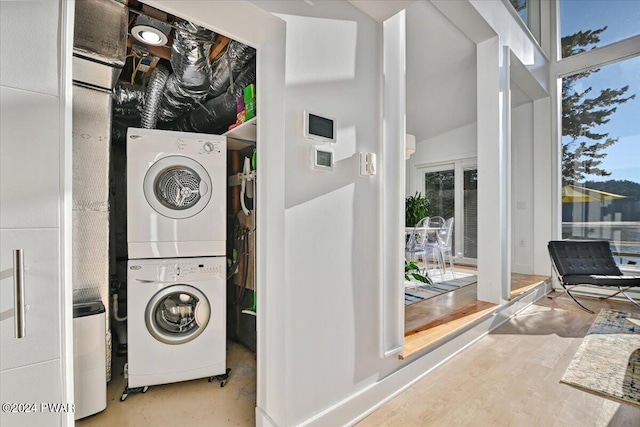 clothes washing area featuring stacked washer and dryer and light wood-type flooring