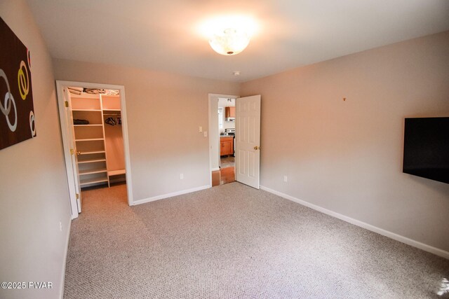 139 Westwood Dr, Dingmans Ferry, PA 18328 - unfurnished bedroom with a walk in closet, light carpet, a closet, and baseboards