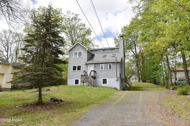 139 Westwood Dr, Dingmans Ferry, PA 18328 - view of front facade with a chimney, gravel driveway, a shingled roof, and a front yard