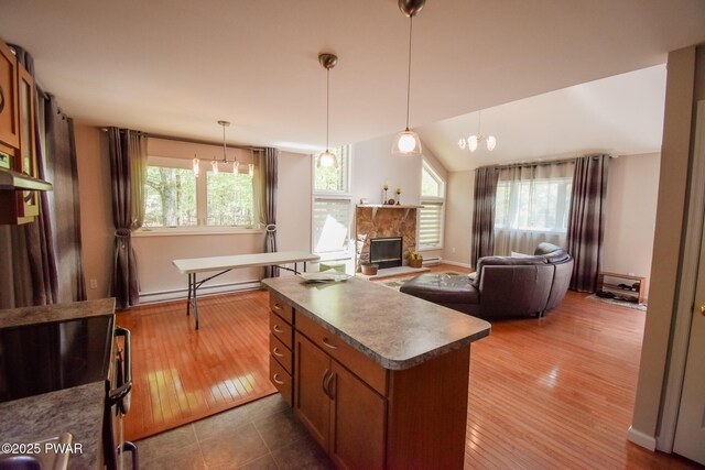 139 Westwood Dr, Dingmans Ferry, PA 18328 - kitchen featuring a kitchen island, range with electric cooktop, brown cabinets, wood finished floors, and a fireplace