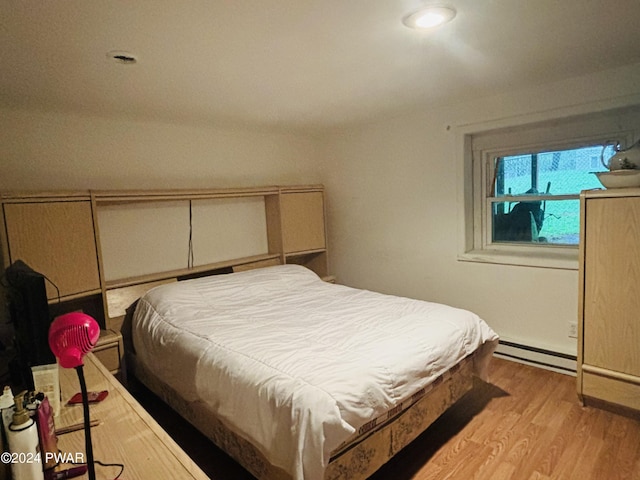 bedroom featuring a baseboard heating unit and light wood-type flooring