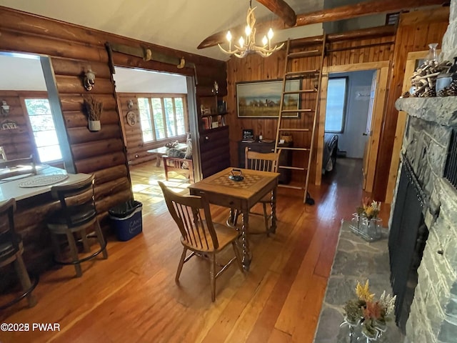22 Glen Rd, Lake Ariel, PA 18436 - dining space featuring a stone fireplace, a chandelier, hardwood / wood-style flooring, healthy amount of natural light, and rustic walls
