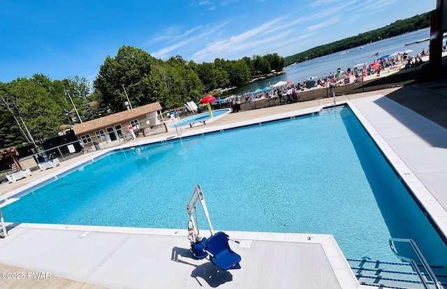 community pool featuring a patio area, a water view, and fence