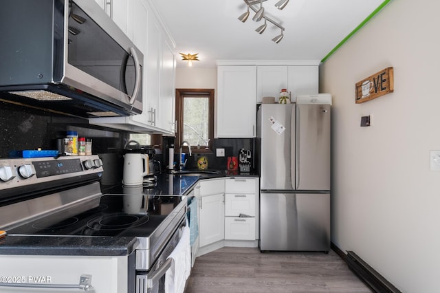 kitchen featuring dark countertops, light wood-type flooring, a sink, white cabinets, and stainless steel appliances
