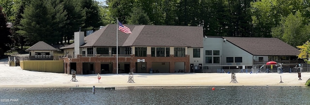 back of property with a water view and a chimney