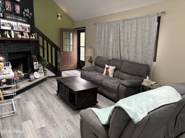 living area with high vaulted ceiling, wood finished floors, and a fireplace