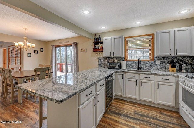 98 Roamingwood Rd, Lake Ariel, PA 18436 - kitchen featuring a sink, white range with gas stovetop, an inviting chandelier, a peninsula, and wine cooler