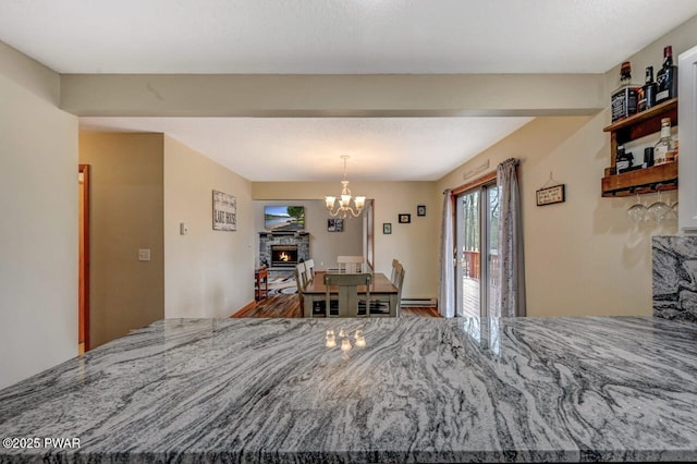 98 Roamingwood Rd, Lake Ariel, PA 18436 - dining area with baseboard heating, wood finished floors, a fireplace, and a chandelier