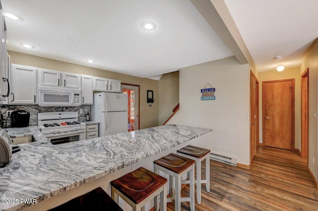 98 Roamingwood Rd, Lake Ariel, PA 18436 - kitchen with a peninsula, wood finished floors, white appliances, light stone counters, and a baseboard radiator