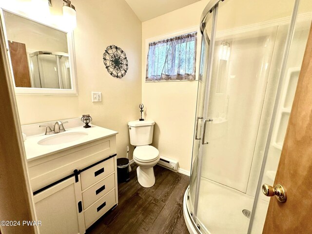 bathroom with vanity, wood-type flooring, a shower with door, and a baseboard heating unit