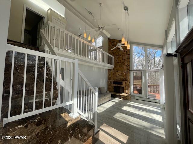 unfurnished living room with a fireplace, a high ceiling, and ceiling fan