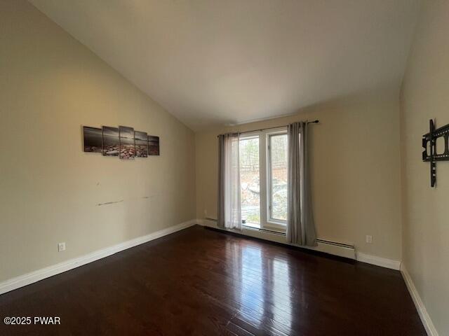 empty room featuring lofted ceiling, baseboards, and dark wood-style flooring