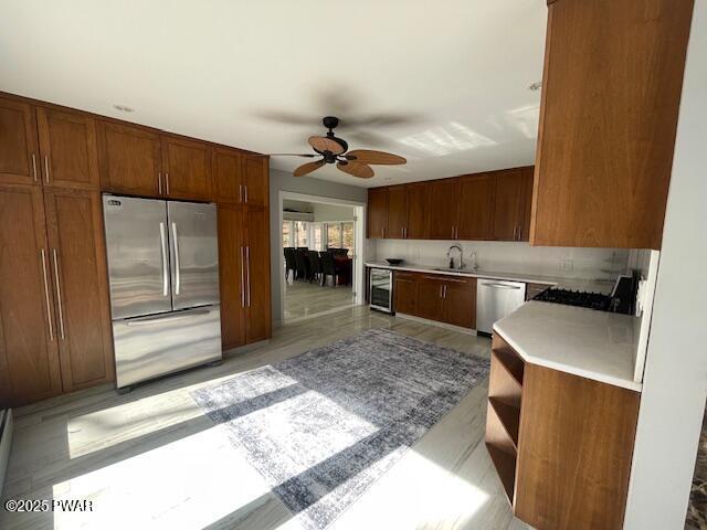 kitchen with open shelves, a sink, stainless steel appliances, light countertops, and wine cooler