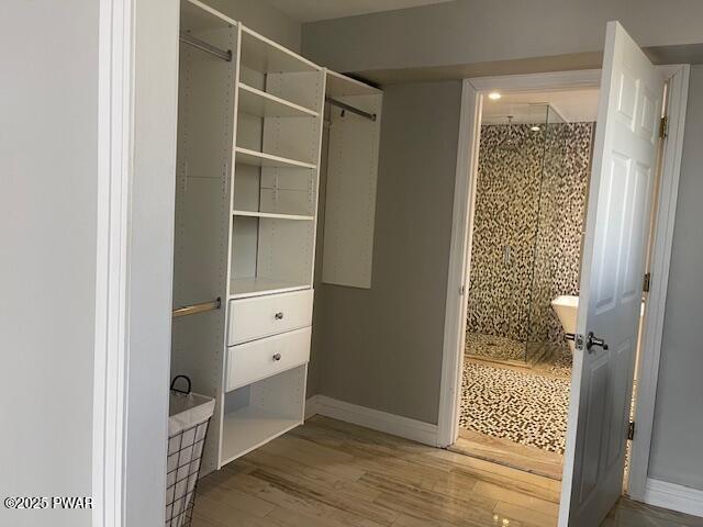 bathroom featuring a stall shower, baseboards, and wood finished floors