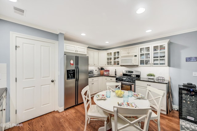 136 Weasel Rd, Dingmans Ferry, PA 18328 - kitchen featuring appliances with stainless steel finishes, light wood-style floors, dark countertops, crown molding, and glass insert cabinets
