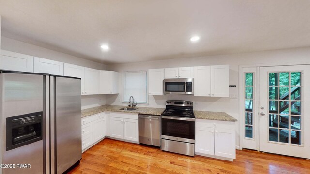152 Fairview Dr, Dingmans Ferry, PA 18328 - kitchen featuring appliances with stainless steel finishes, a sink, white cabinetry, light stone countertops, and light wood finished floors