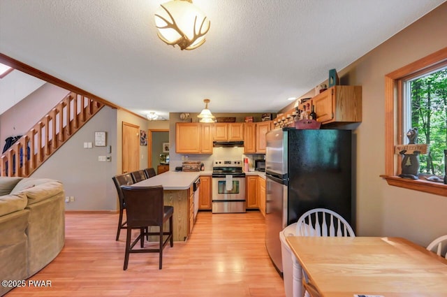 108 Minnow Ct, Lackawaxen, PA 18435 - kitchen featuring stainless steel appliances, under cabinet range hood, light wood-style flooring, a breakfast bar area, and a textured ceiling