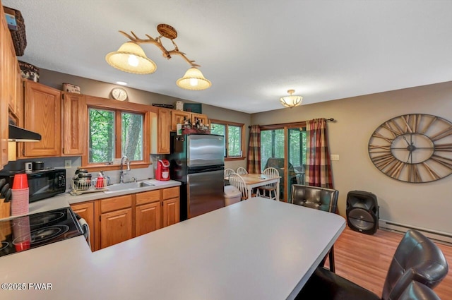 108 Minnow Ct, Lackawaxen, PA 18435 - kitchen featuring freestanding refrigerator, black microwave, light countertops, under cabinet range hood, and a baseboard radiator