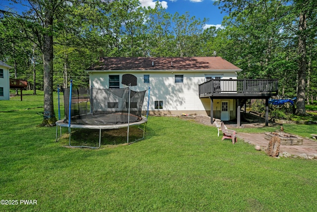 135 Kiel Rd, Milford, PA 18337 - back of property with a trampoline, a wooden deck, a lawn, and a fire pit