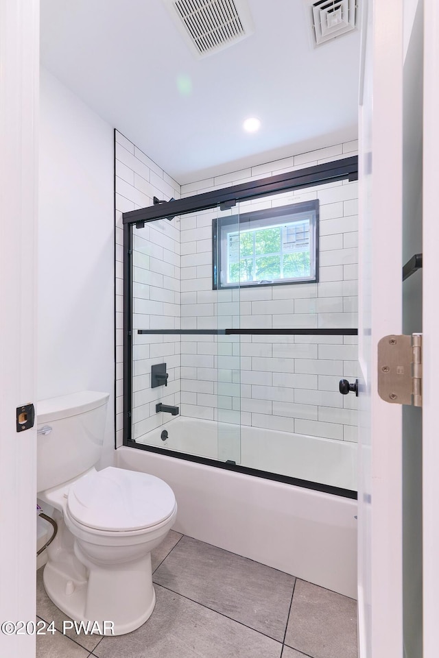 bathroom with bath / shower combo with glass door, tile patterned floors, and toilet