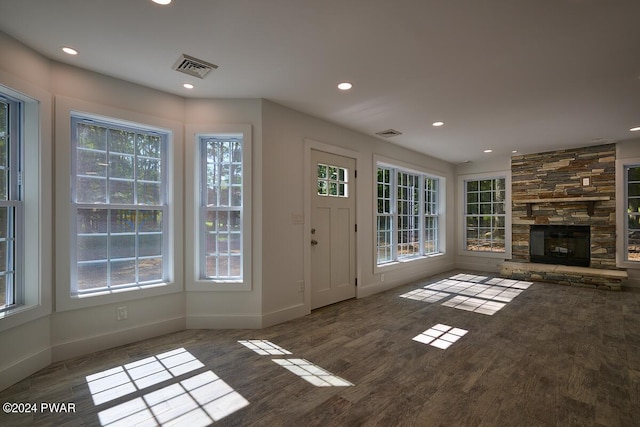 unfurnished living room featuring dark hardwood / wood-style floors and a stone fireplace