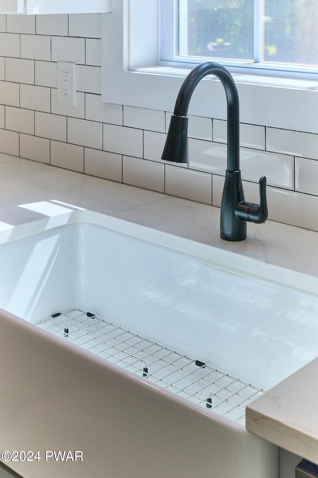 room details with tasteful backsplash, sink, and light stone counters