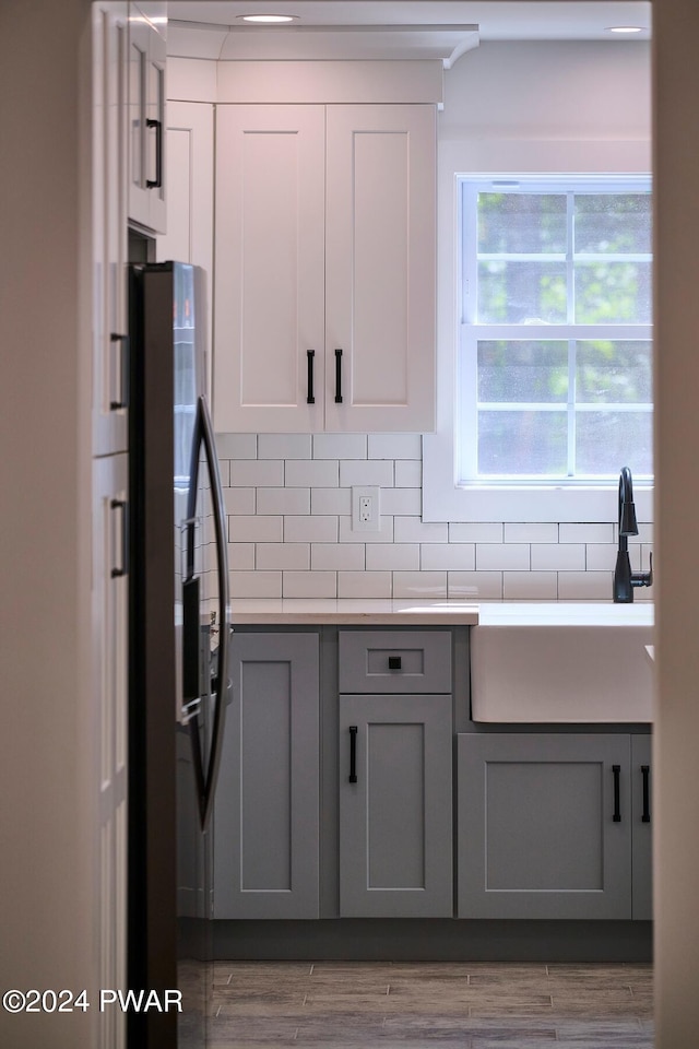 kitchen with sink, light hardwood / wood-style flooring, fridge, gray cabinets, and backsplash