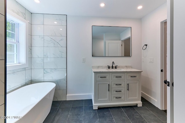 bathroom featuring tile patterned flooring, vanity, a bath, and tile walls