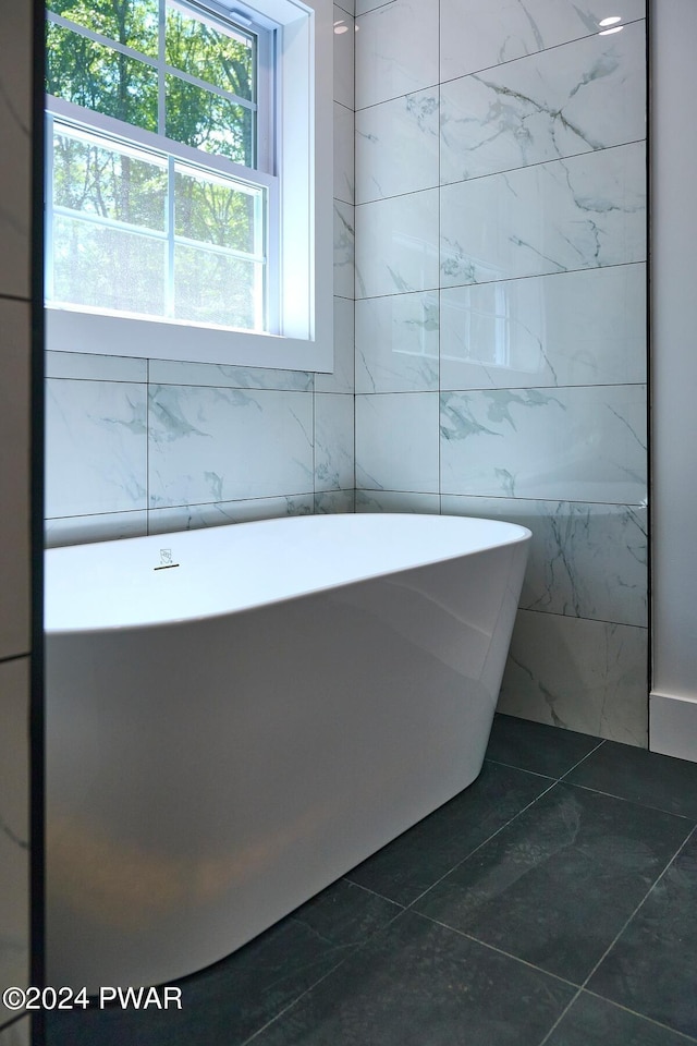 bathroom featuring tile patterned floors, tile walls, and a tub