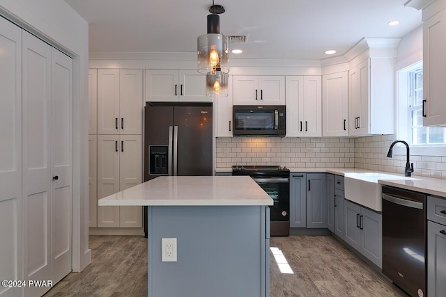 kitchen with sink, black appliances, hanging light fixtures, a kitchen island, and backsplash