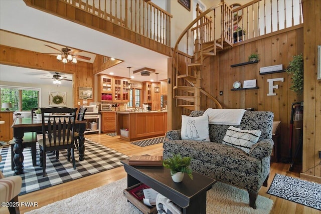 141 Arrowhead Cir, Newfoundland, PA 18445 - living area featuring a towering ceiling, wood walls, ceiling fan, stairs, and light wood-style floors