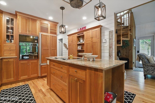 141 Arrowhead Cir, Newfoundland, PA 18445 - kitchen featuring black appliances, light wood-style flooring, light stone counters, a center island, and wood walls