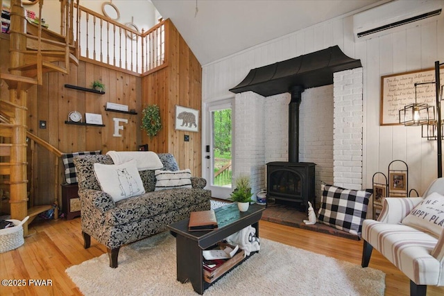 141 Arrowhead Cir, Newfoundland, PA 18445 - living room with a wall unit AC, wood walls, a wood stove, wood finished floors, and high vaulted ceiling