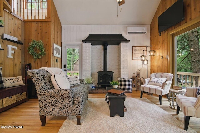 141 Arrowhead Cir, Newfoundland, PA 18445 - living area featuring plenty of natural light, a wood stove, an AC wall unit, wood finished floors, and wooden walls
