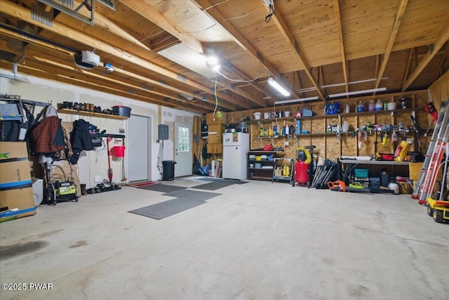 141 Arrowhead Cir, Newfoundland, PA 18445 - garage with a garage door opener, freestanding refrigerator, and a workshop area
