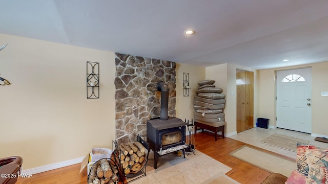 living area featuring a wood stove, baseboards, and wood finished floors