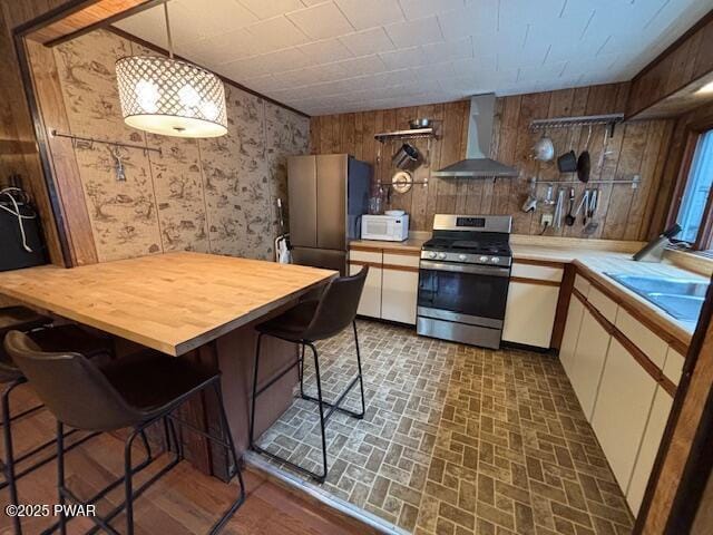 30 Bear Hill Rd, Lake Ariel, PA 18436 - kitchen featuring wall chimney range hood, appliances with stainless steel finishes, white cabinets, brick patterned floors, and butcher block countertops