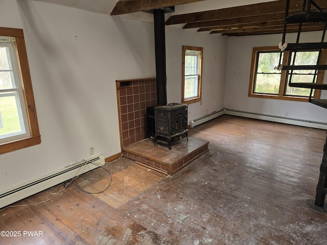 unfurnished living room with wood finished floors, a wood stove, and a baseboard heating unit