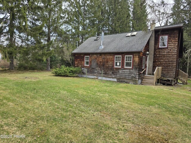 back of house featuring a lawn, a shingled roof, and a chimney