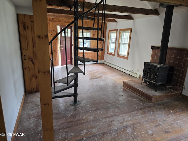 unfurnished living room featuring a wood stove, wood-type flooring, stairway, and a baseboard radiator
