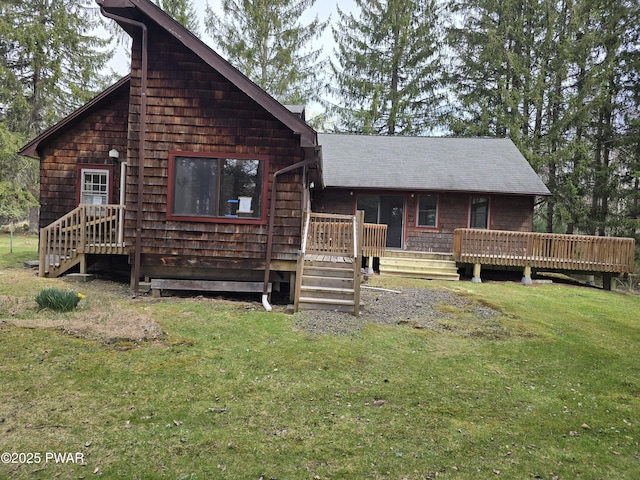 view of front of home with roof with shingles, a front yard, and a deck