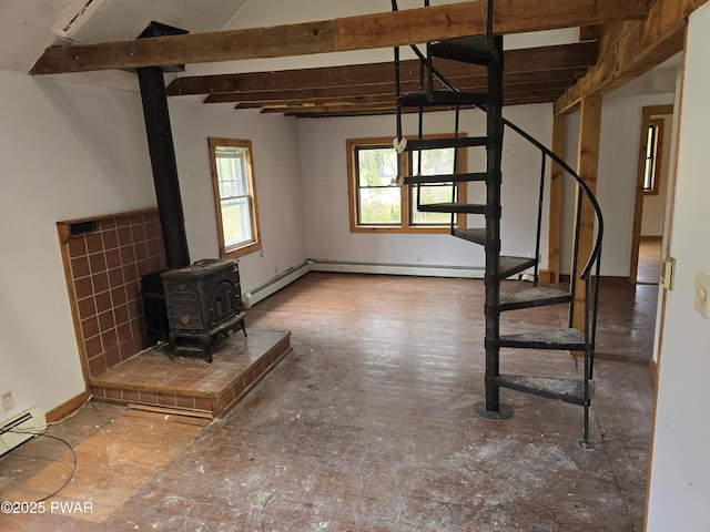 basement featuring stairway, baseboard heating, and a wood stove