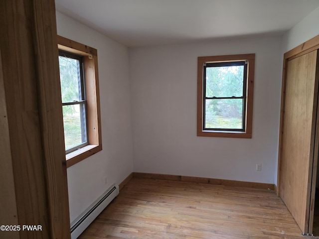 unfurnished bedroom featuring light wood-type flooring, baseboard heating, and multiple windows
